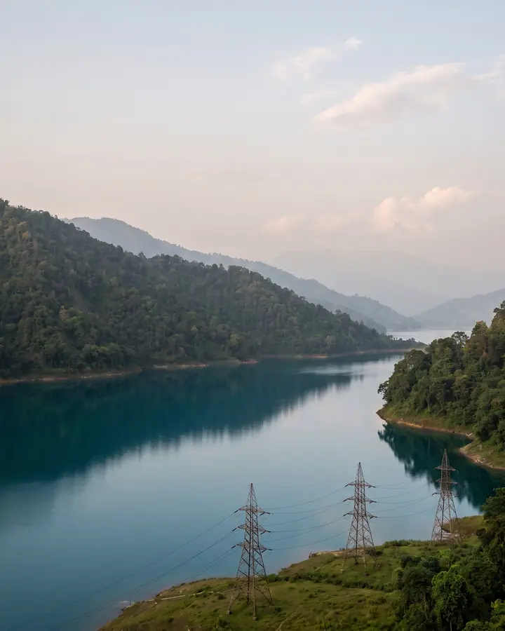A calm lake between forested hills, with power lines along its shore.