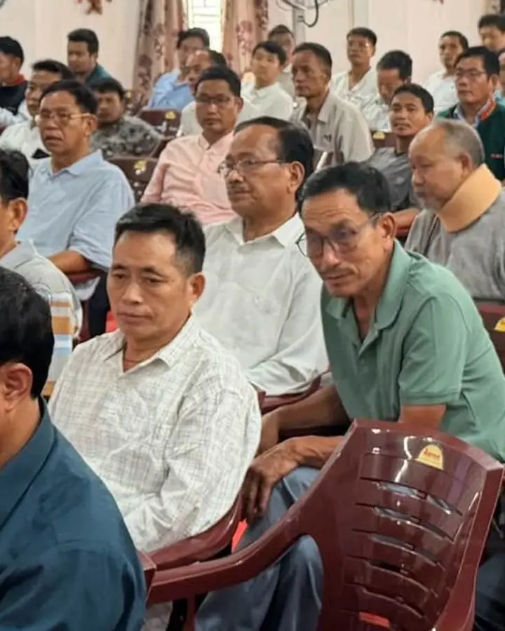Photo of community members seated at a meeting in a hall.